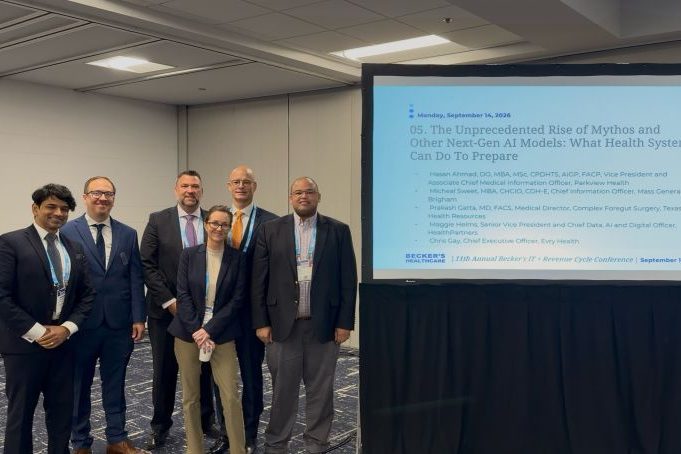 Six panelists standing together beside a screen showing the session “The Unprecedented Rise of Mythos and Other Next-Gen AI Models: What Health Systems Can Do To Prepare,” dated Monday, September 14, 2026, at Becker’s 11th Annual IT + Revenue Cycle Conference.