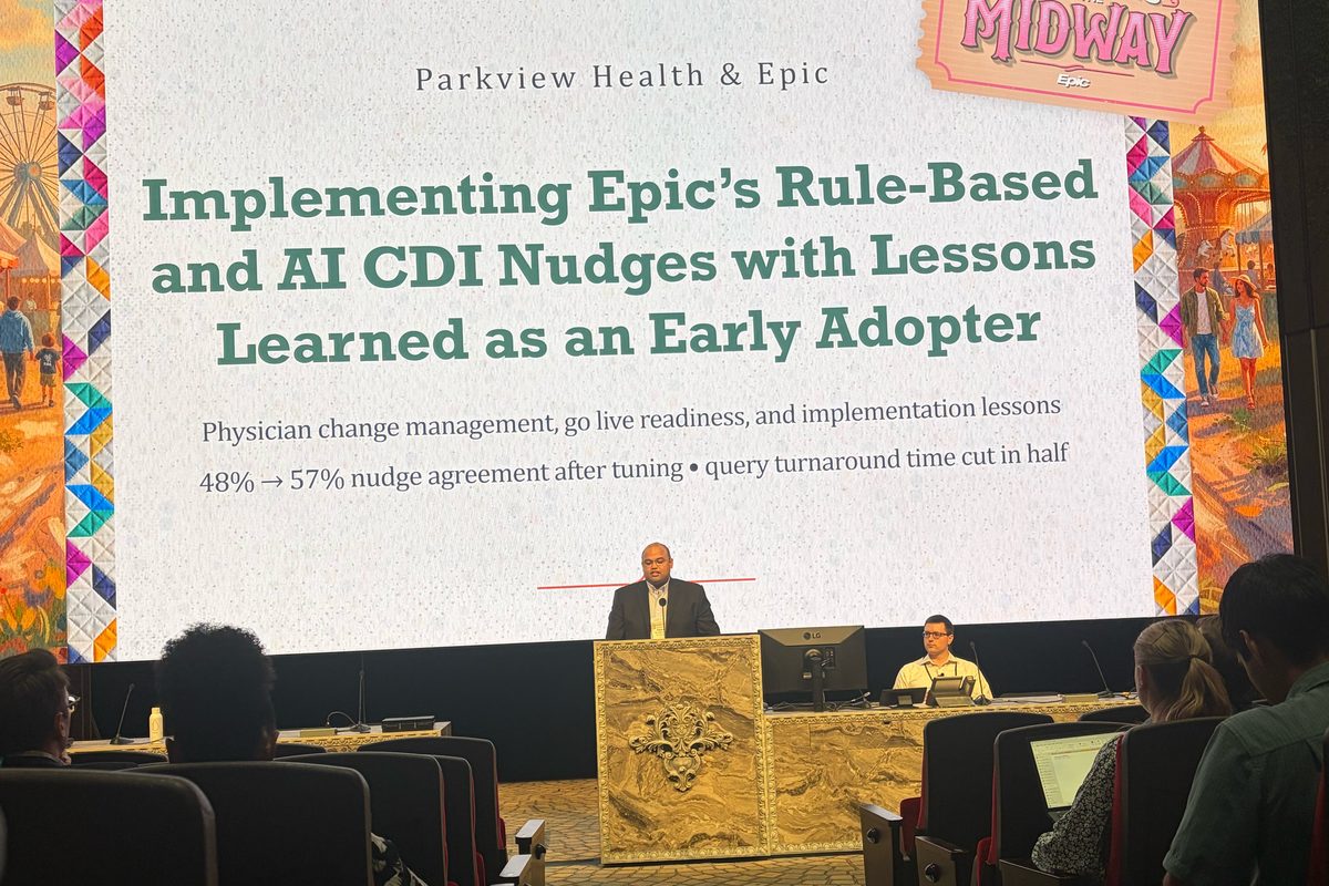 Hasan Ahmad speaking at a podium on stage beneath a large screen reading “Parkview Health & Epic: Implementing Epic’s Rule-Based and AI CDI Nudges with Lessons Learned as an Early Adopter,” with a “Meet Me at the Midway” Epic banner, as the audience watches from tiered seats.